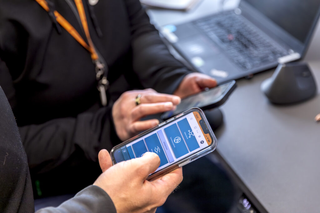 Two professionals using Plenaxy on mobile devices to manage HSEQ tasks and safety reporting